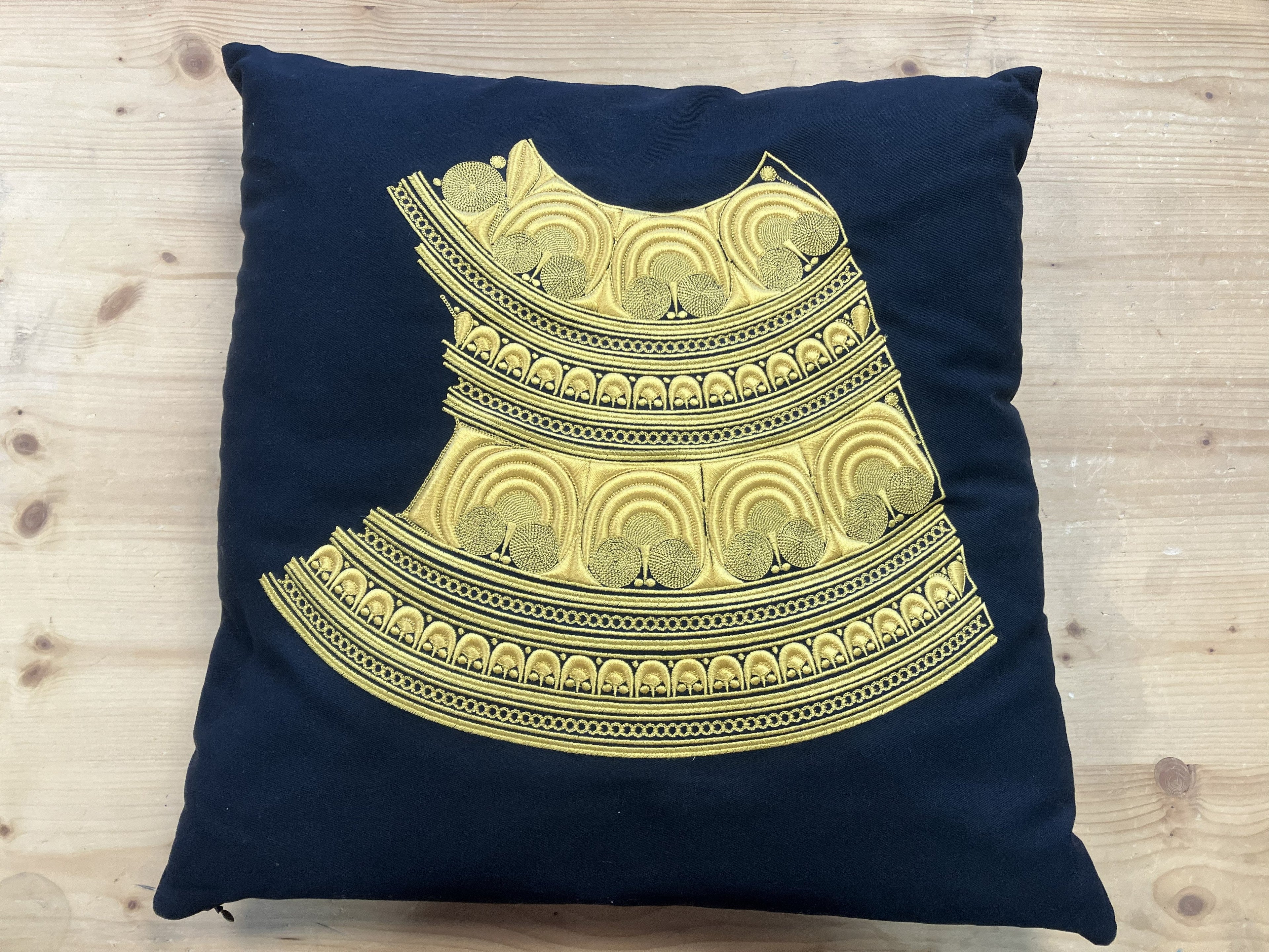 Broderie de plume de paon sur tissu noir tenu devant un port breton